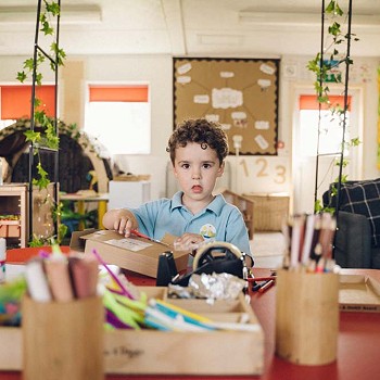 plentyn ifanc wrth fwrdd yn gwneud celf a chrefft