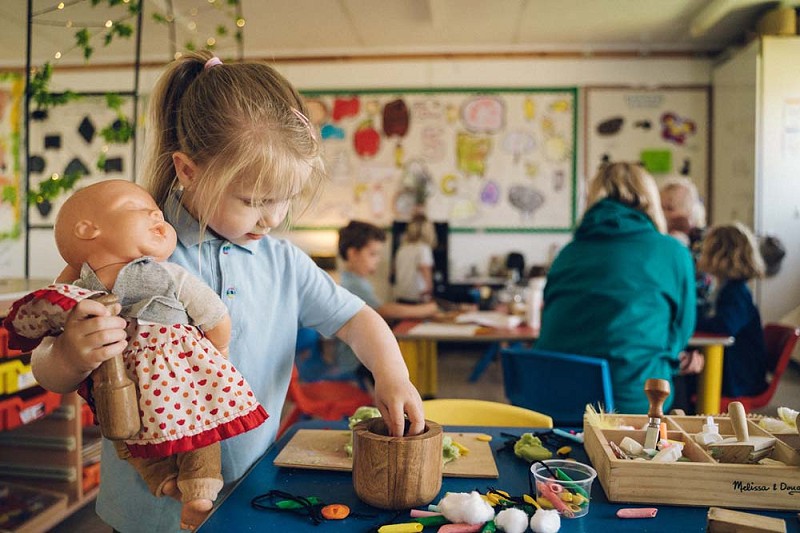 myfyrwr yn gafael mewn ddol wrth gwneud celf